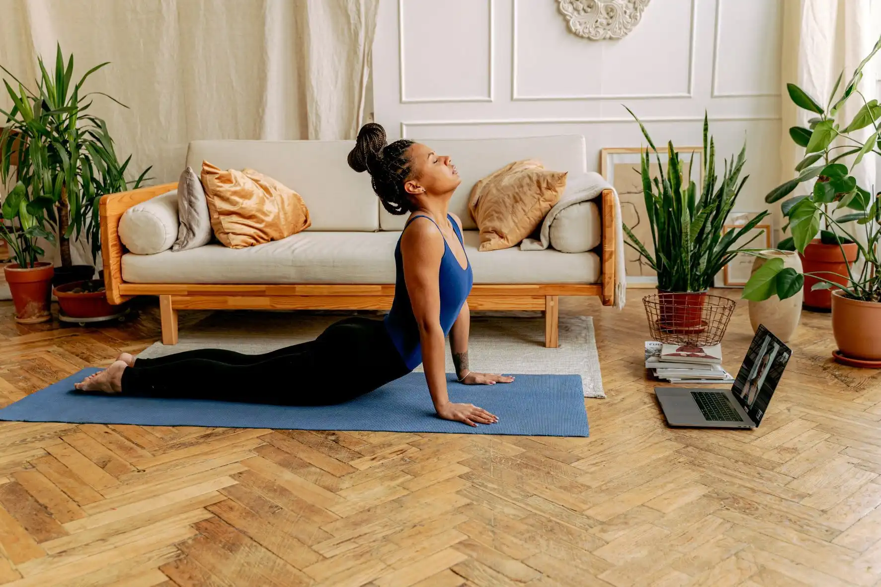 Une personne dans son salon en train de faire du yoga, et plus exactement la posture du cobra